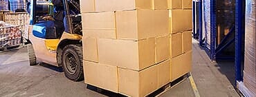 Forklift beside stacked cartons in a warehouse